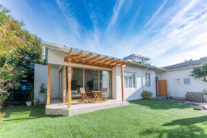見学会場となる二世帯の平屋。木のパーゴラを掛けた共用のウッドデッキと芝の庭