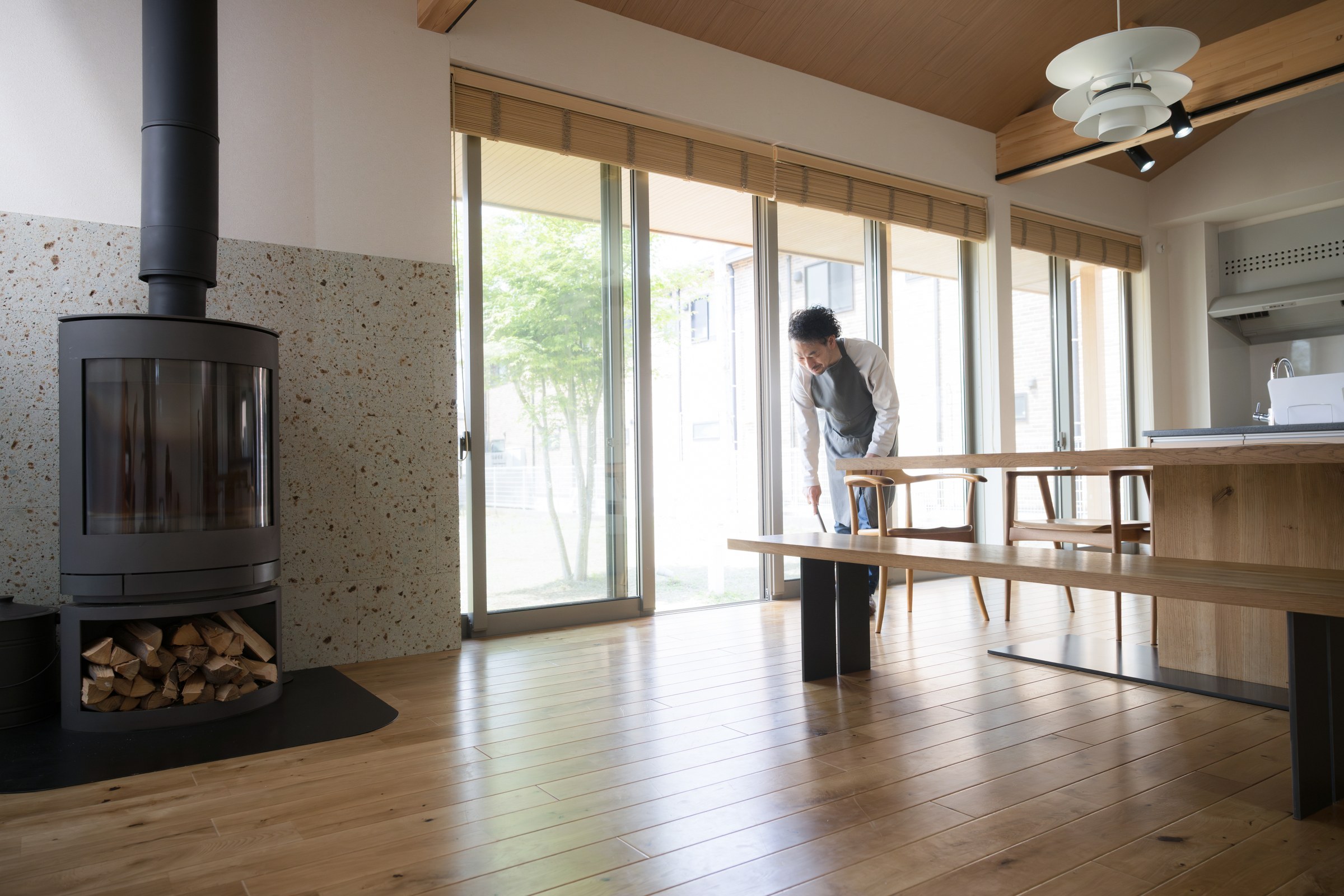 勾配天井に薪ストーブ、無垢の床。庭へ開く大開口のある平屋のリビングダイニング
